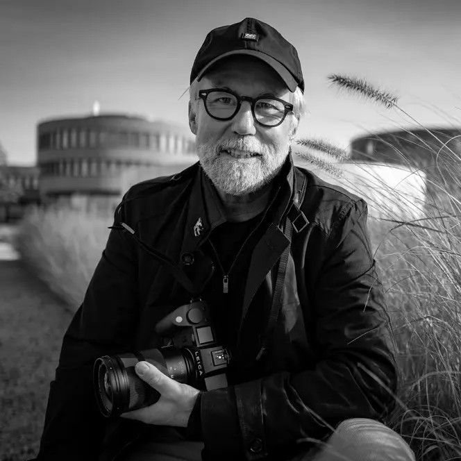 Portrait of photographer Ragnar Axelsson holding a Leica camera