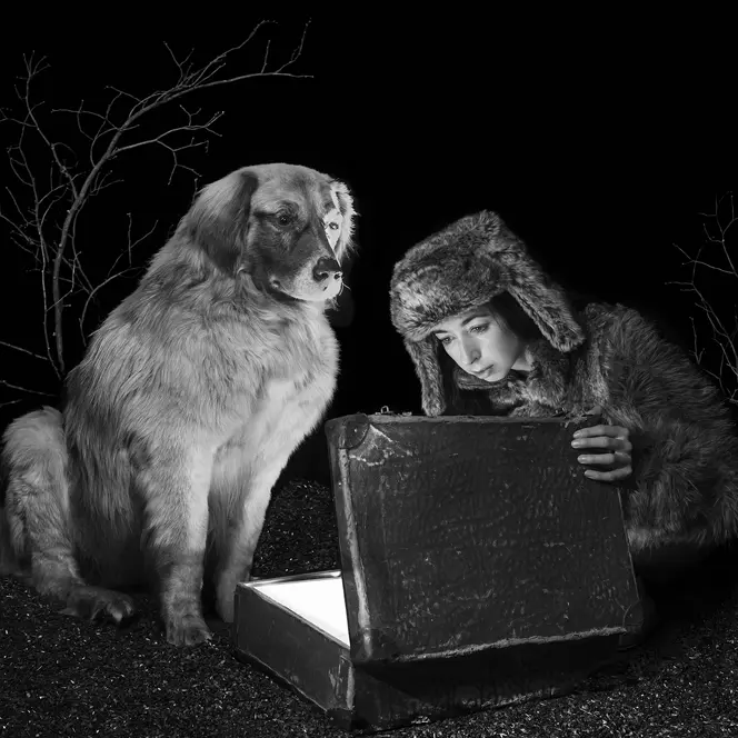 Viktoria Sorochinski and a dog looking into an old suitcase that is glowing inside. 