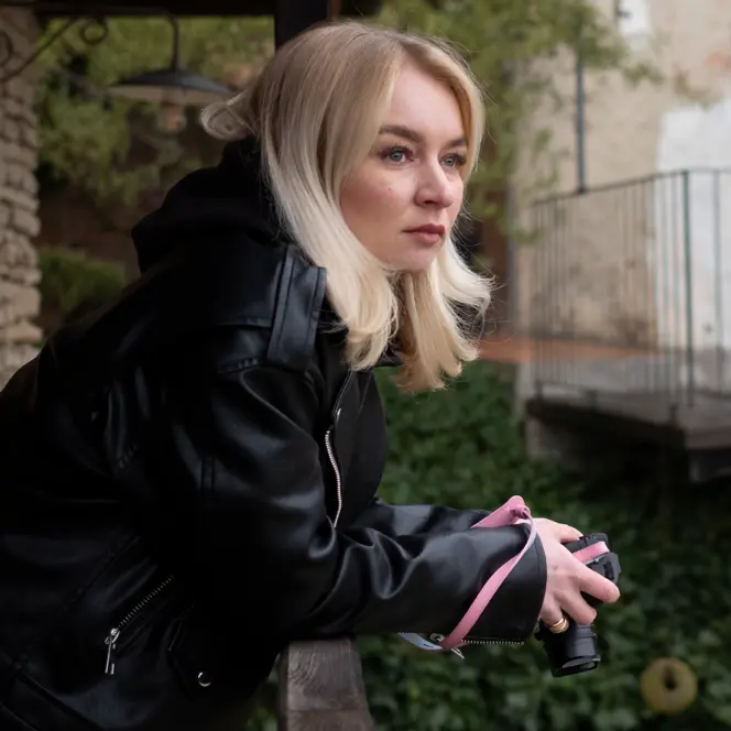 Woman on a balcony holding a camera in her hands.