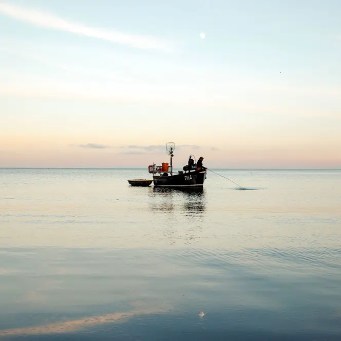 A person in a small boat fishing in the sea.