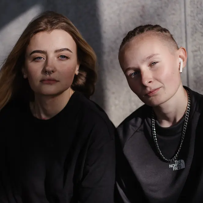 Two women sitting together and looking directly at the camera.