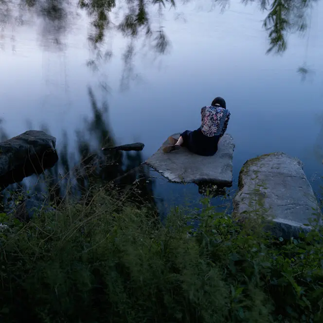 Woman sitting on a stone by the lake
