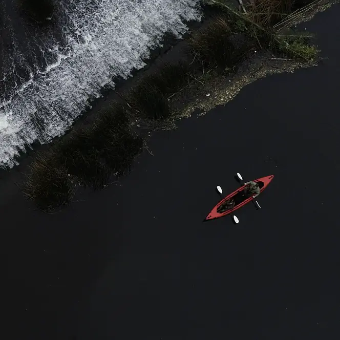 Red canoe paddling along the black sea coast.