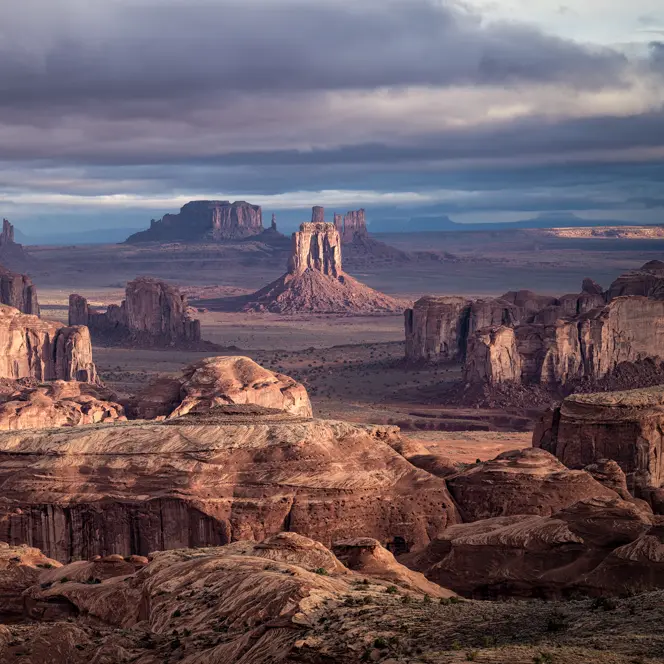 Vast desert landscape with remarkable rock formations under a cloudy sky.