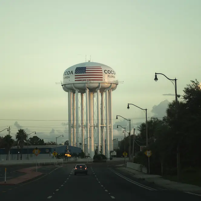 An empty road leads to a water tower labelled ‘Cocoa, Florida’.