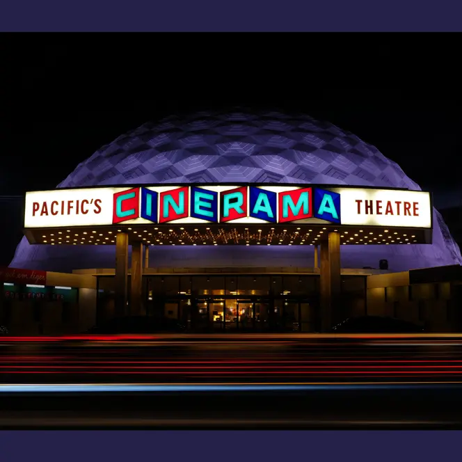Luminous Cinerama theatre at night.