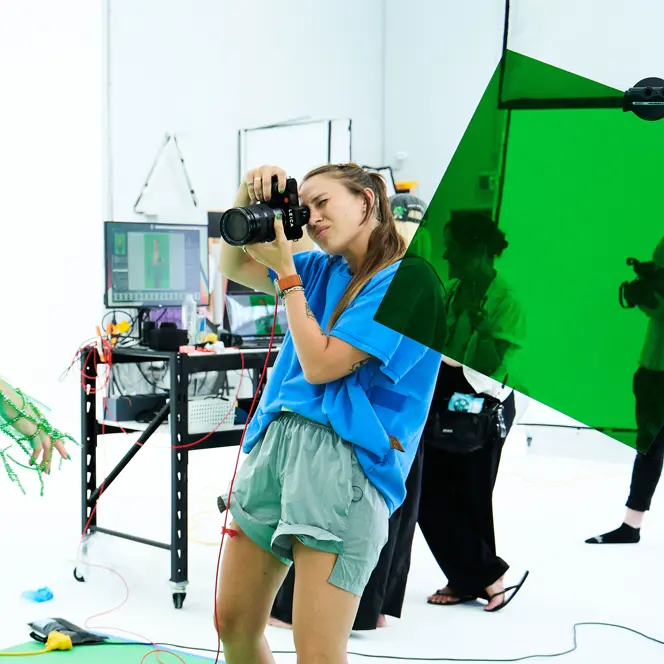 Photographer takes a picture in a studio of a model in a green net outfit.
