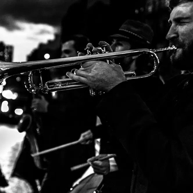 Several musicians and a trumpeter in the foreground play music in the street