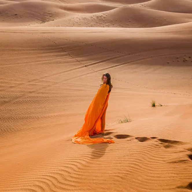 Woman in an orange dress standing in the desert.