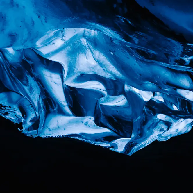 A glowing blue ice formation in a dark cave.