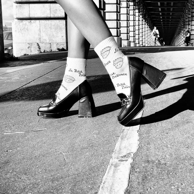 Close-up of legs in high heels on a street under a bridge in black and white.