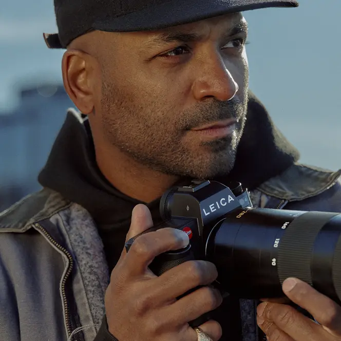 Close-up of a man holding a camera with skyscrapers in the background. 