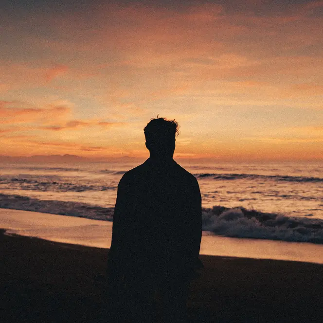 Silhouette of a man watching the sunset on the beach.