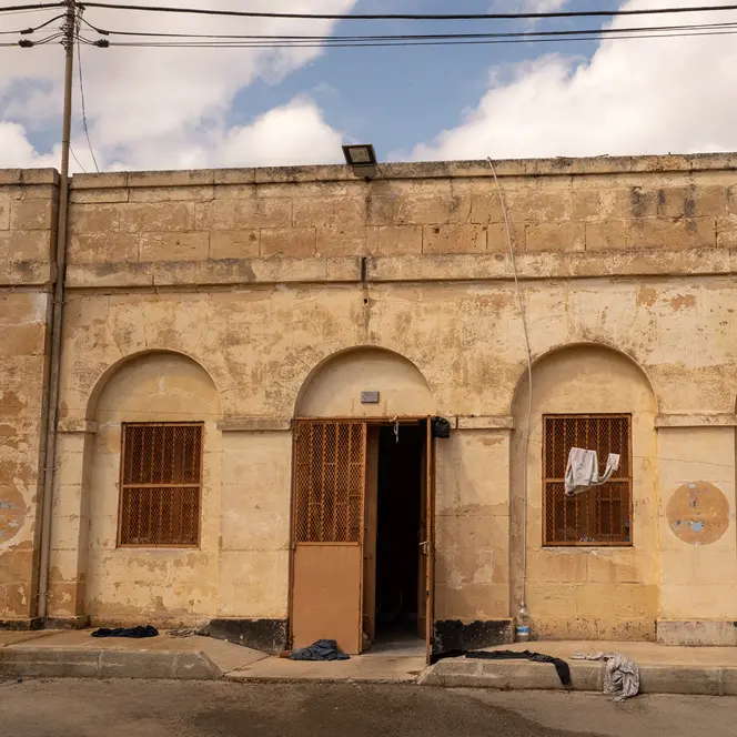 Older stone building with barred windows and clothes hanging outside.