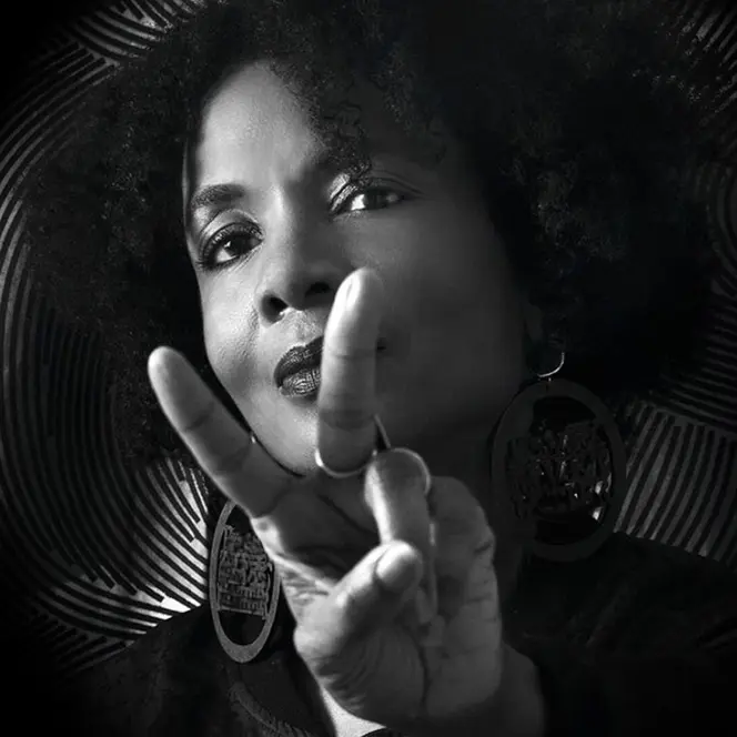 Black and white portrait of a woman with an Afro hairstyle making the peace sign