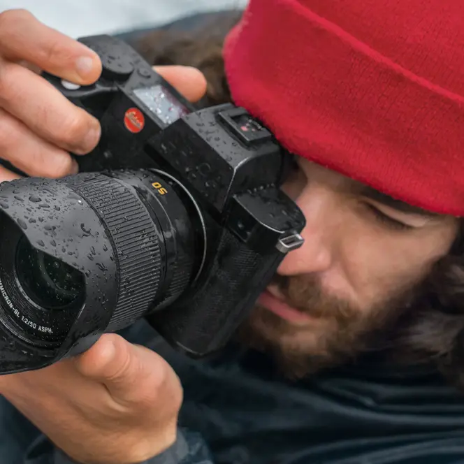 Close-up of a photographer with a red cap looking through the camera