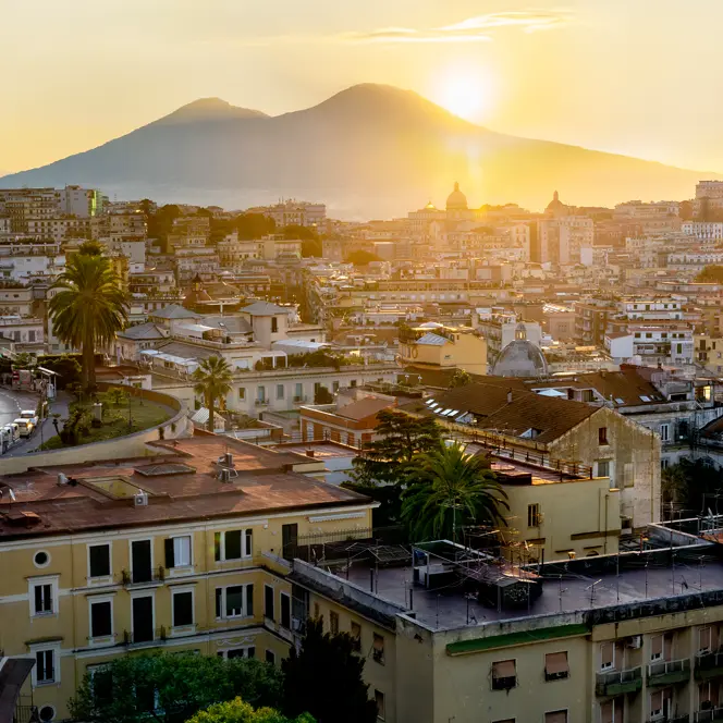 Italian city and the sun setting behind a mountain.