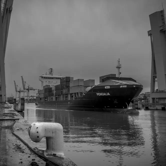 Container ship in the harbour, surrounded by cranes and containers