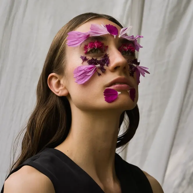 Ein Portrait einer Frau mit Blumen auf ihrem Gesicht.