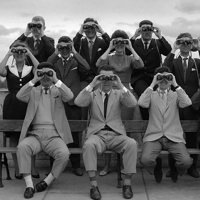 Women and men in 1960 with binoculars in front of their faces