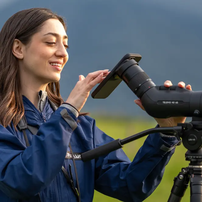 Woman is digiscoping with her Leica Televid and Smartphone