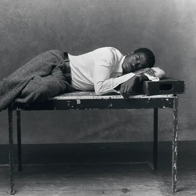 Portrait en noir et blanc de l'acteur Damson Idris allongé sur une table