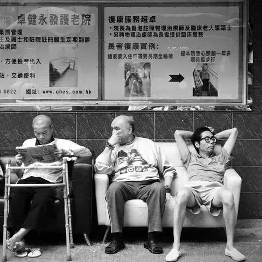 people sitting on bench at bus stop blakc and white