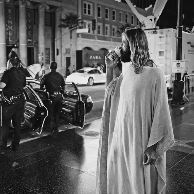 man in a jesus cosplay eating icecream b&w