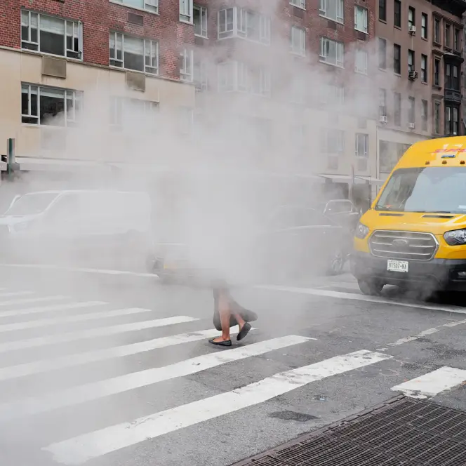 A woman walks along a pavement through the fog