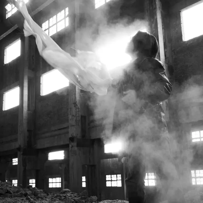 Black-and-white photograph of a man holding a white cloth in an empty old building