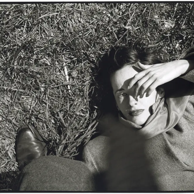 Frau liegt im im Gras und hält sich Hand ins Gesicht, Saul Leiter