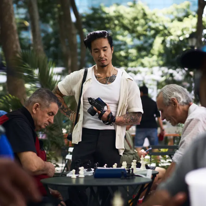 Documentary photograph of photographer Billy Dinh observing a chess game in a New York City park with a Leica Q, capturing everyday street photography and urban life.