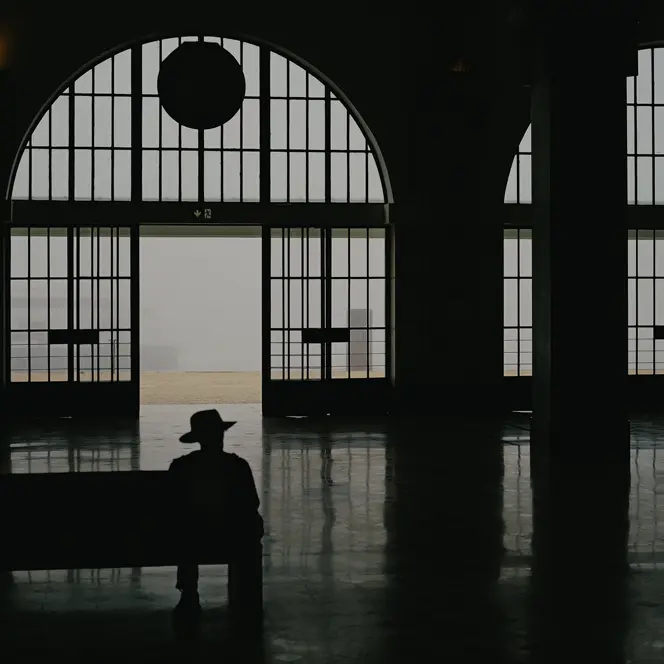 Ombre d'un homme assis dans une gare avec un chapeau