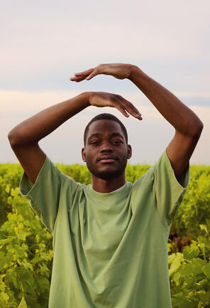a black man in a green T-shirt with his arms in the air