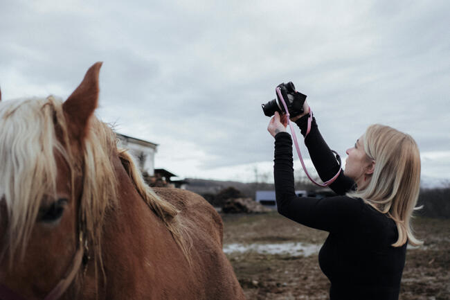 A woman photographs a horse
