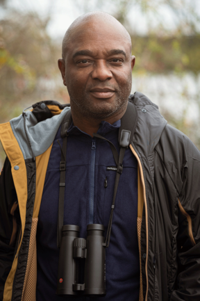 Portrait of David Lindo with a pair of Leica binoculars