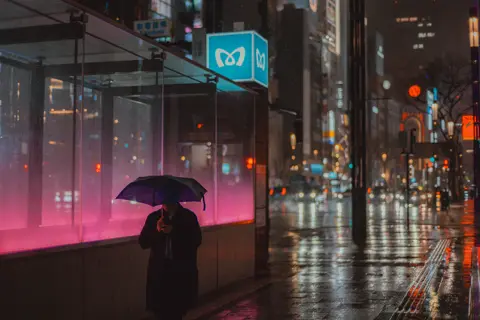 Man walks through rainy streets with umbrella