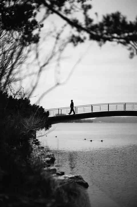 A picture of a man crossing a bridge at Lake Biel