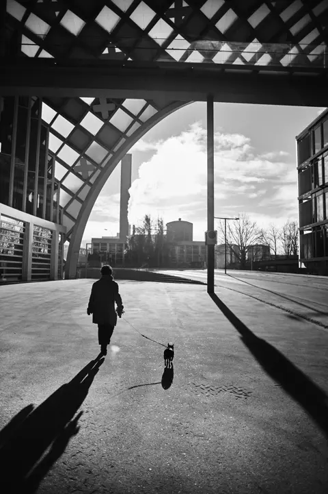 An image of a person walking their dog at the Swatch museum in Biel