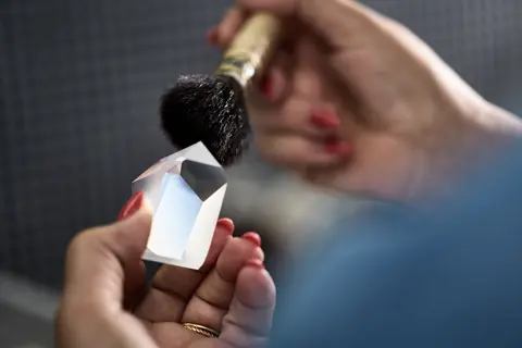 A Leica employee is cleaning the prisms of a Leica spotting scope