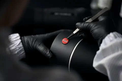 A Leica employee is sticking a Leica logo on the Leica spotting scope