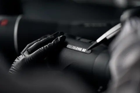 A Leica employee is sticking a Leica product name batch on the Leica spotting scope