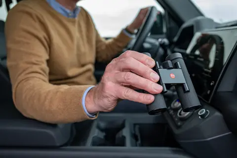 Man in a car is using his Leica Noctivid Compact