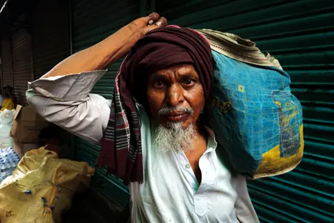 An old man with a large sack on his shoulders