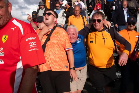 Formula 1 fans leave the grandstand at the Dutch Grand Prix in Zandvoort, many wearing orange and Ferrari fan apparel.