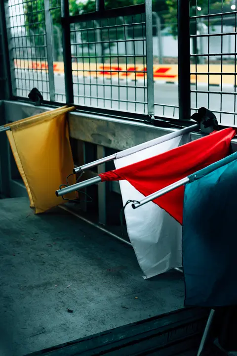 Yellow, white, red and blue flag by the fence at the racecourse