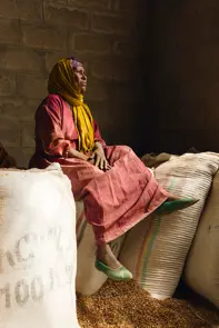 A woman sitting on large sacks of grain