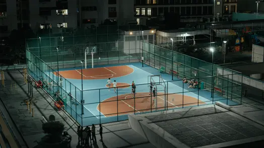 A bird's-eye view of a floodlit basketball court at night