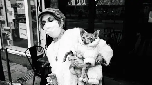 Black and white photograph of a lady holding a dog with a cigarette in her hand.