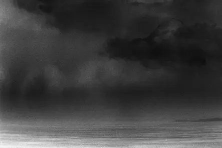 Schwarzweißes analoges Meeresbild mit dunklen Sturmwolken über dem Ozean.